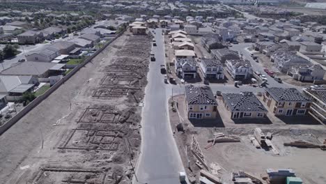 A-high-overview-drone-shot-captures-a-home-construction-site,-revealing-the-transformation-from-bare-lots-to-lots-with-people-moved-in,-showcasing-the-dynamic-progress-of-the-residential-development