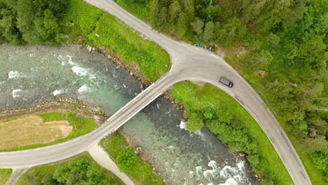 el vehículo pasa por un pequeño puente sobre un curso de agua en geiranger, noruega