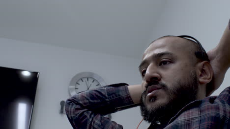 Close-up-shot-of-man-wearing-headset-and-thinking-while-sitting-in-the-chair