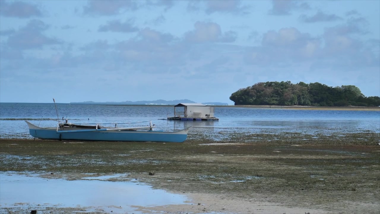 Siargao Kıyısında Ahşap Tekne ve Yüzen Kulübe - Arka Planda Yemyeşil Ada ve Bulutlu Gökyüzü - Geniş Çekim