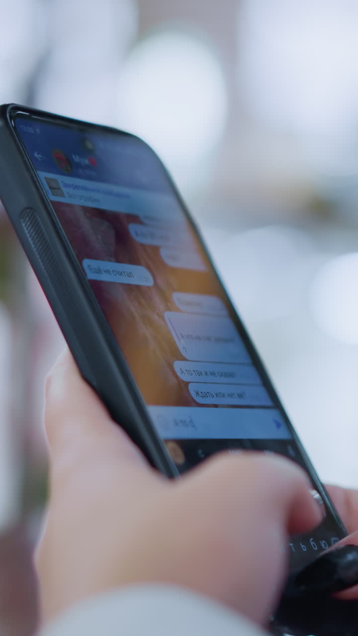 primer plano de alguien escribiendo a mano o hablando en un teléfono inteligente con un fondo suave y borroso con luces bokeh, capturando un momento de comunicación digital en un entorno moderno y relajado
