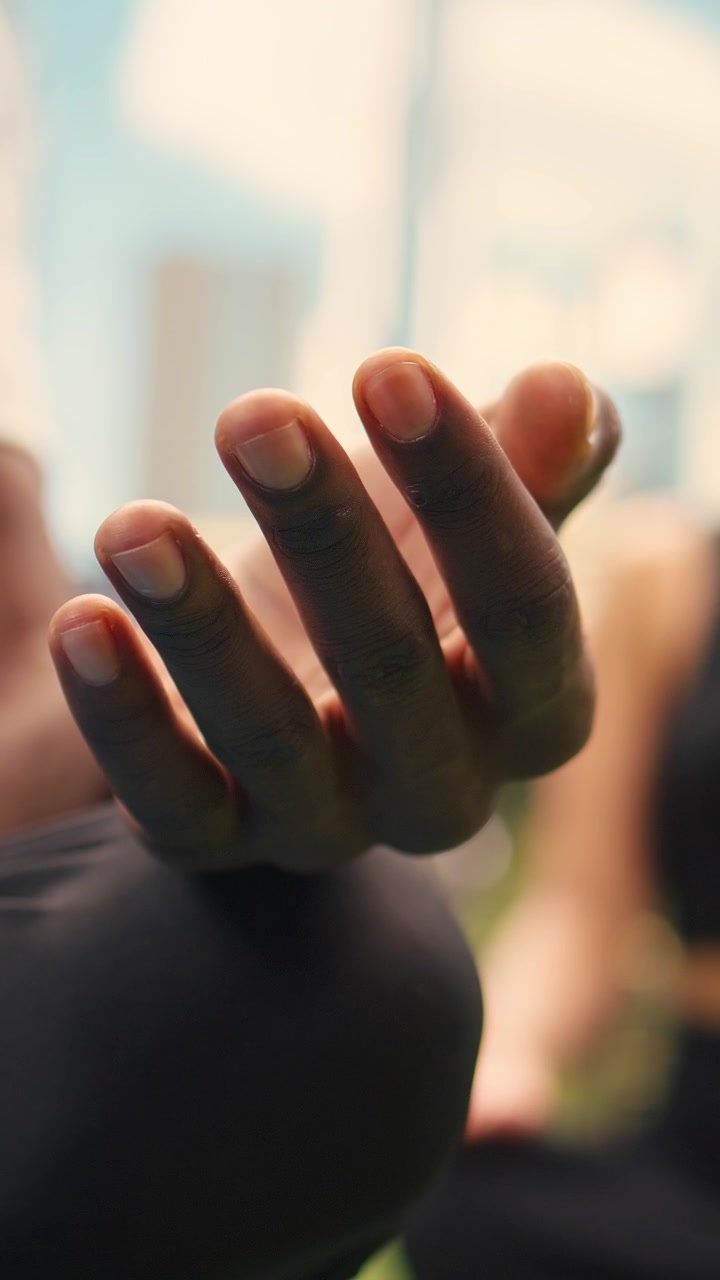 Vídeo vertical em close de homem com a mão aberta em gesto de meditação enquanto está sentado de pernas cruzadas