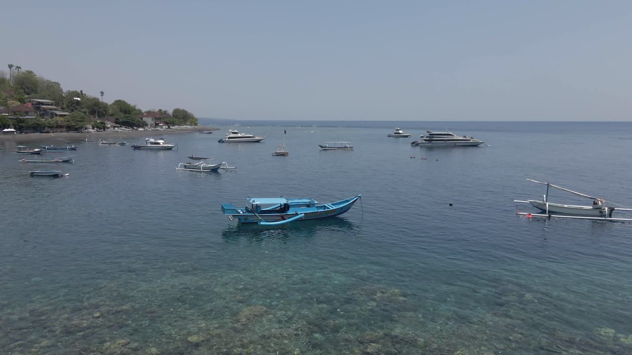 Flyover outrigger boats moored off Jemeluk pebble beach on Bali
