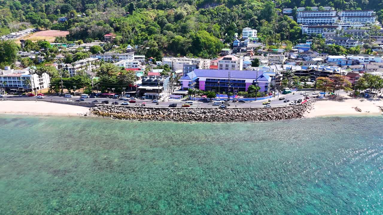 드론 영상은 푸켓의 활기찬 해안선을 포착합니다. 은 물, 활기찬 도시, 밝은 낮빛 아래 울창한 초록색