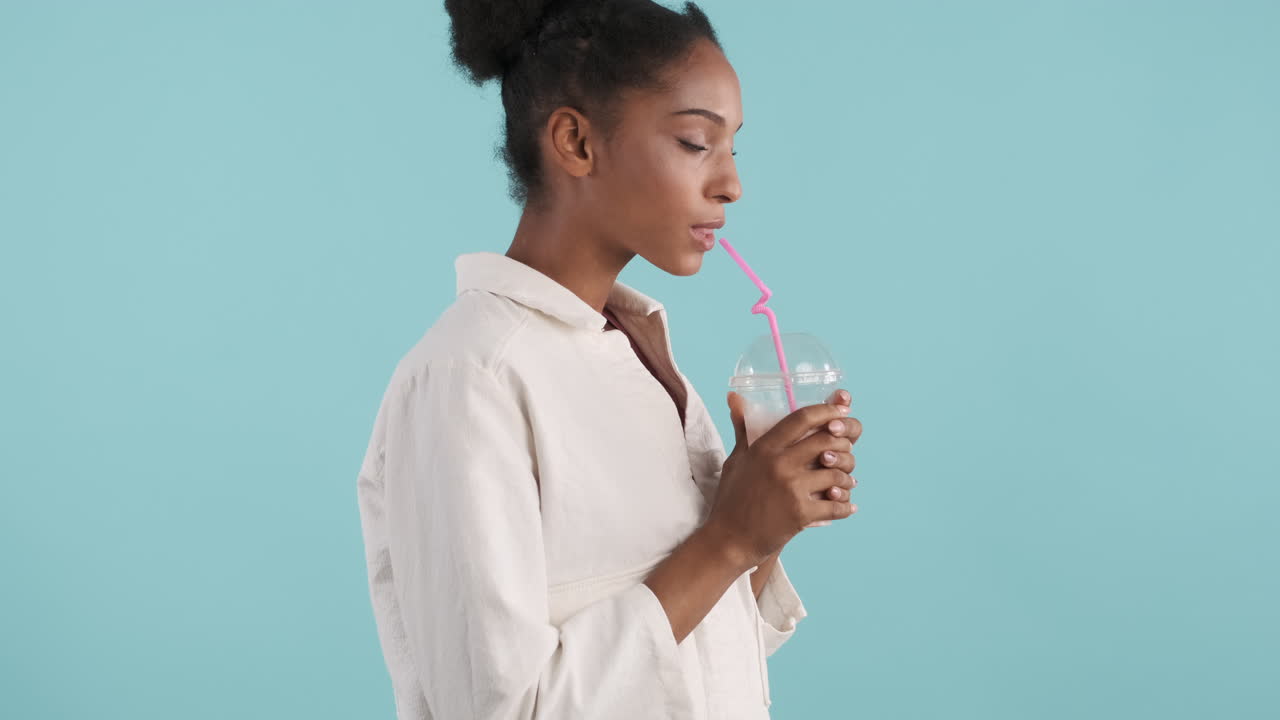 vista lateral de una mujer joven bebiendo un batido