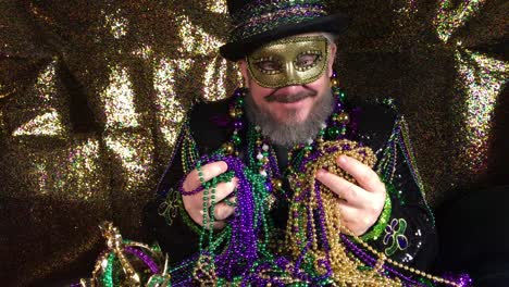 feliz mardi gras hombre disfrazado con sombrero de copa sosteniendo un montón de cuentas