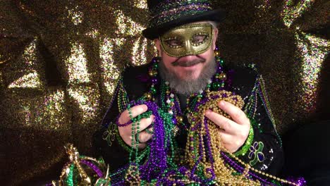 happy mardi gras man in fancy costume with top hat holding pile of beads