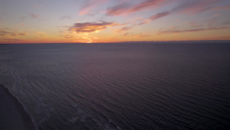 vuelo aéreo sobre el mar tranquilo durante la puesta de sol dorada