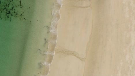 Vertical-Shot-Calm-Waves-Rolling-Onto-Cornish-Coastline-In-St-Ives,-Cornwall,-England