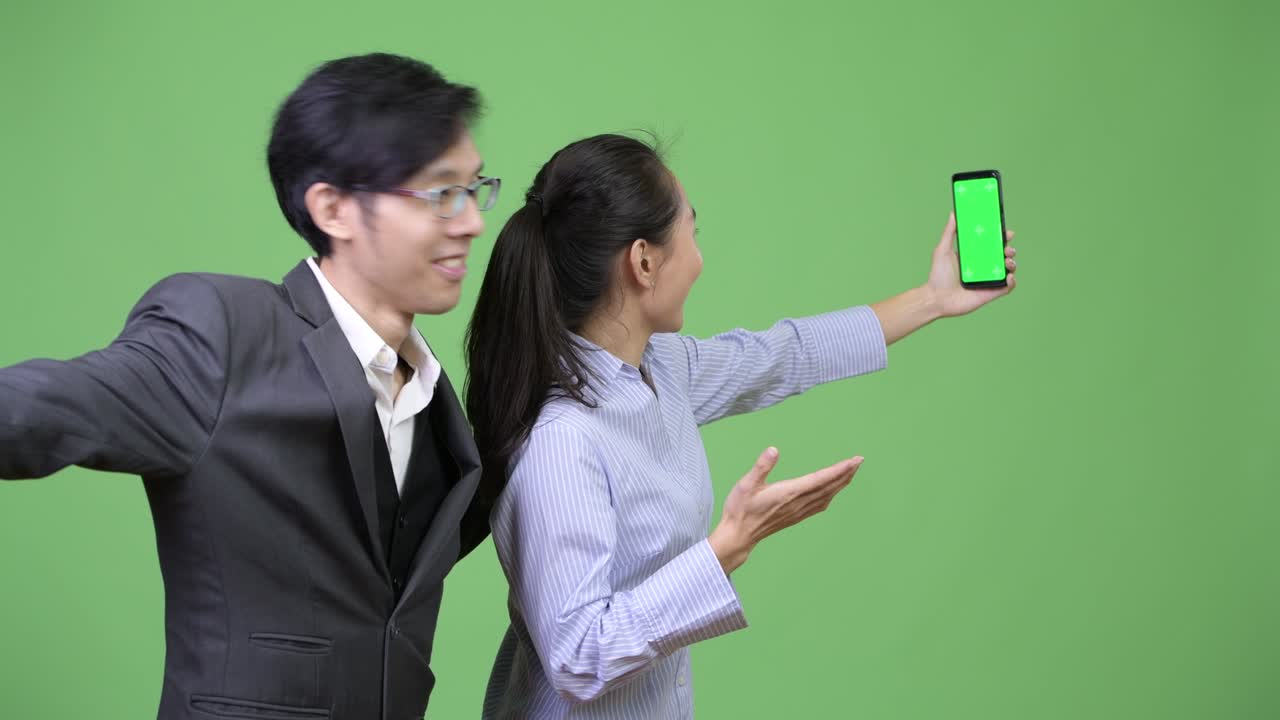 Young Asian business couple showing phone together