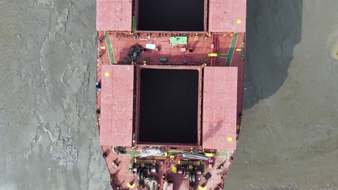 Cinematic epic drone shot going down the length of an abandoned cargo ship in Bangladesh. downward angle