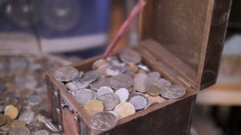 finger opening treasure chest with coins close up