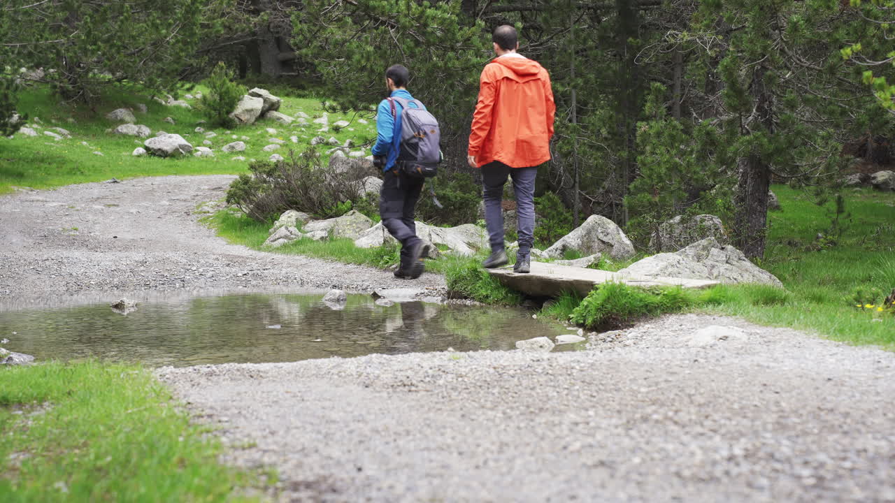 couple of trekker walking on mountains narrowed path Aig&uuml;estortes National Park located in the Catalan Pyrenees Spain