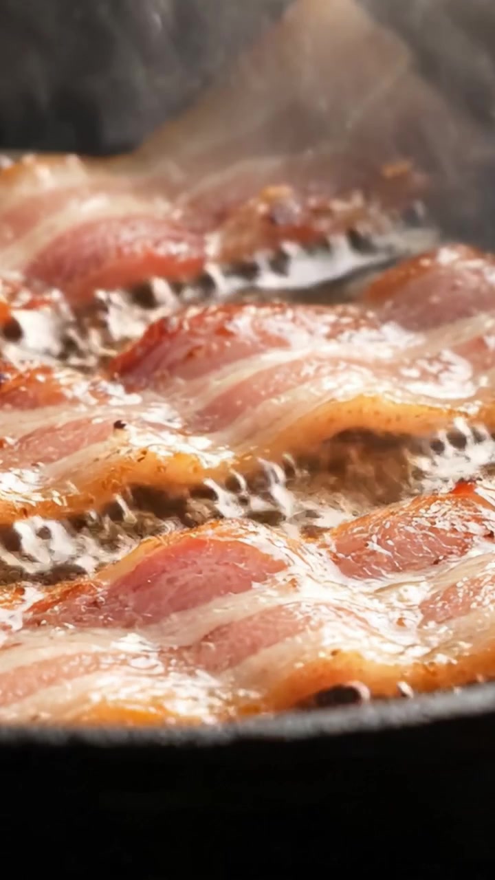 Pancetta Deliziosamente Sfrigolante che Cuoce in una Padella Calda: Uno Sguardo Ravvicinato a Striscioline di Maiale Croccanti che Sciolgono il Grasso e si Glassano in Modo Irresistibile