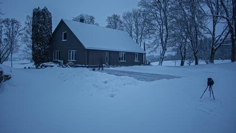 Un-Hombre-Quitando-Nieve-Con-Una-Pala-Limpiando-Nieve-Frente-A-Una-Cabaña-De-Madera-Suburbana-Después-De-Fuertes-Nevadas-En-Un-Día-De-Invierno