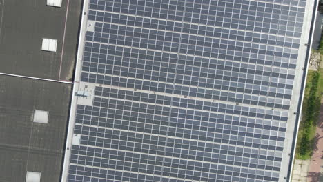 Top-down-aerial-of-photovoltaic-solar-panels-on-flat-rooftop---drone-setting-down