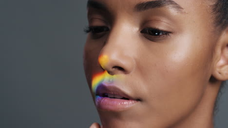 retrato multicolor de cerca hermosa mujer afroamericana tocando el rostro acariciando la piel suave disfrutando del cuidado de la piel belleza con luz colorida que se refleja en la tez suave