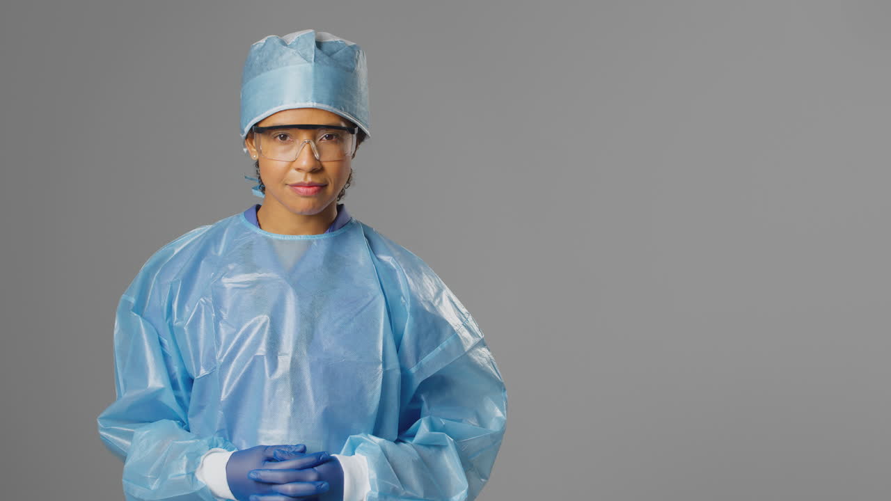 retrato de una cirujana seria con gafas de seguridad contra un fondo gris