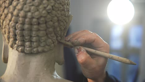 워크 ⁇ 에서 특별한 도구를 사용하여 부처 동상 머리카락을 작업하는 인식 할 수없는 예술가