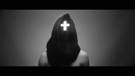 masked man with cross of light glowing on his face makes a 'no' gesture