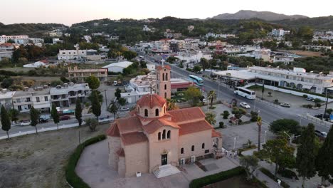 beautiful orange orthodox church in faliraki, rhodes, aerial orbit during sunset