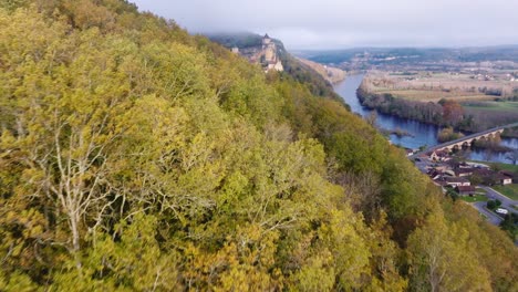 aerial view of a castle on a hillside with a river and bridge