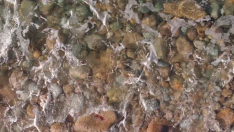 waves crashing on pebbles and rocks on the praia brana de lazo in camariñas, a coruña, spain