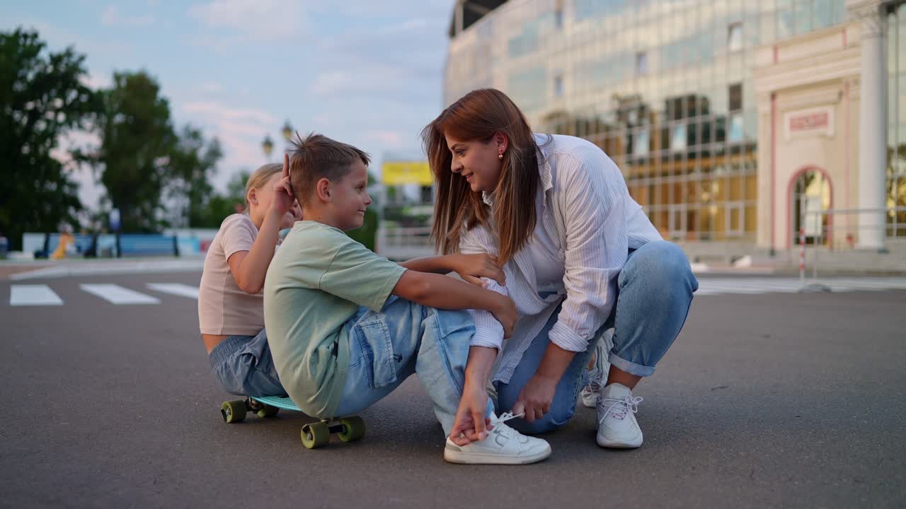 madre ayudando a los niños con los patinetes