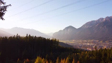 Areal-drone-overview-of-the-city-of-Innsbruck,-mountains-in-the-background-at-sunset