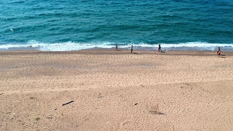 Flying-over-the-beach-with-a-drone,-while-people-walking-along-the-sea-in-Sardaigna,-dunes-of-Piscinas