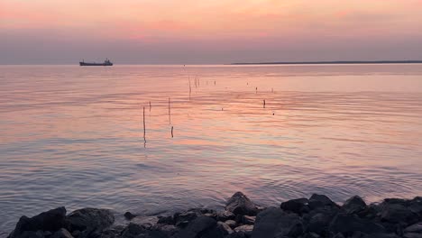 vista serena de la puesta de sol con el mar tranquilo y las rocas