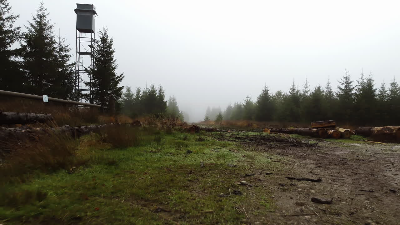 un avión no tripulado retrocede en un bosque cubierto de niebla revelando una torre de vigilancia en bélgica