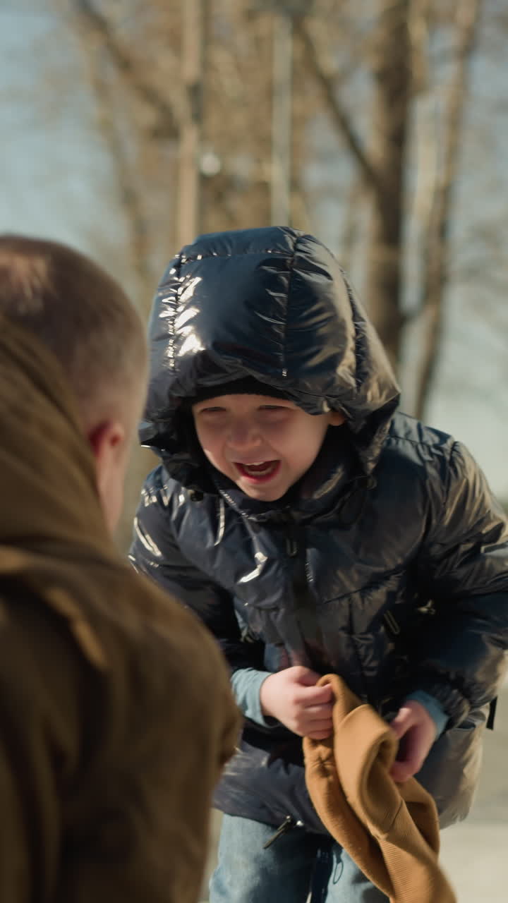 un padre y un hijo jugando mientras el hijo arrastra el gorro marrón del padre de su cabeza mientras ambos comenzaban a reír emocionados