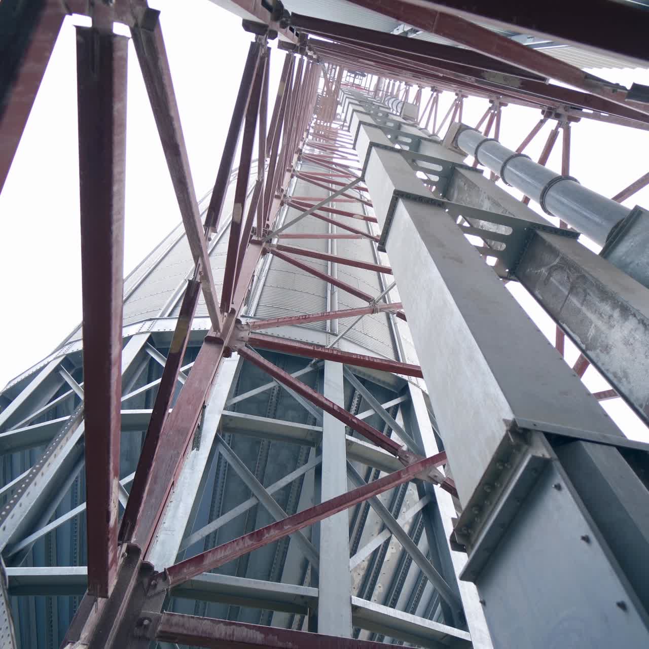 Pipes and supports at the grain-drying complex. High steel constructions at the backdrop of sky. View on the structure from below