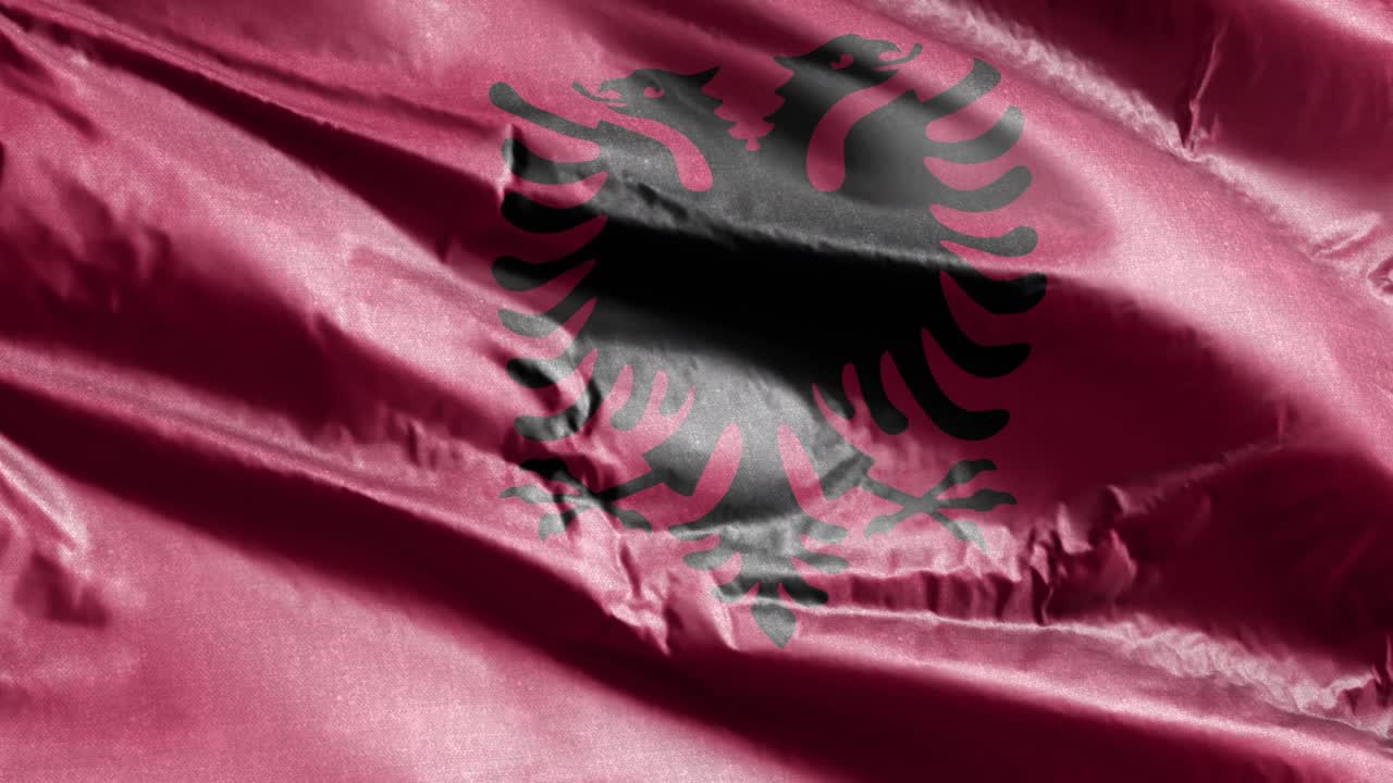 Albania textile flag slow waving on the wind loop. Albanian banner smoothly swaying on the breeze. Fabric textile tissue. Full filling background. 20 seconds loop.