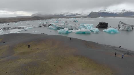 Toma-Aérea-De-Turistas-Viendo-Una-Laguna-Glacial