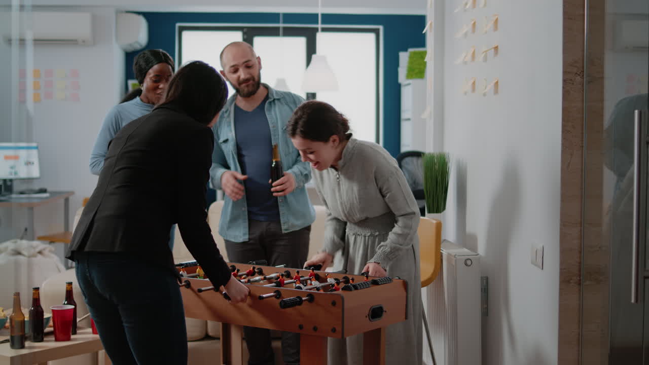 Cheerful women playing at foosball game table after work