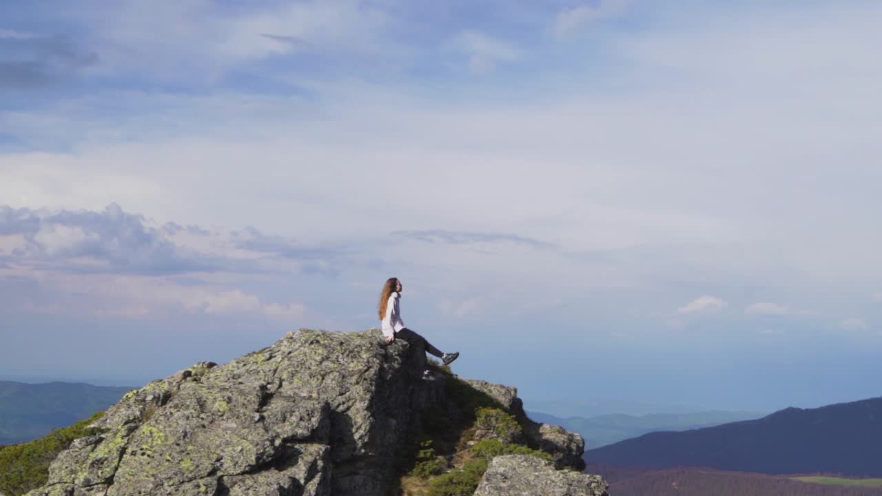 하늘을 바라보는 산 꼭대기에 앉아 있는 여자