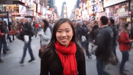 a young woman stands confidently in times square, surrounded by a vibrant crowd. the energy of the city fills the air as lights illuminate the evening sky.