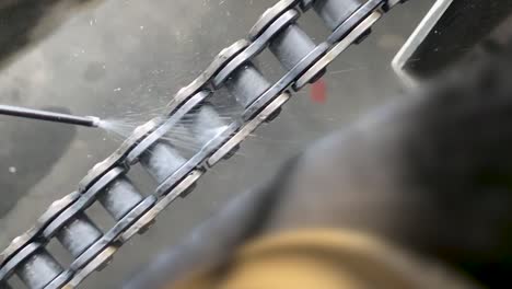 el mecánico está lubricando la cadena de motos con lubricante