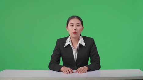 live news studio with professional asian female anchor reporting on the events of the day on the green screen