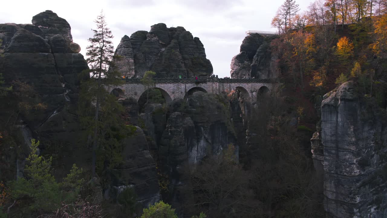 puente bastei de arco de piedra entre acantilados rocosos en el bosque de otoño, alemania