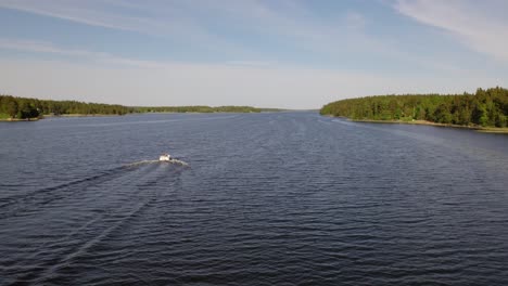 Aerial-view-following-a-boat,-driving-on-the-Baltic-sea,-warm,-sunny,-summer-evening,-in-the-archipelago-of-Sweden---low,-drone-shot