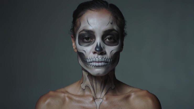 Ripresa di una modella che mantiene la posa, batte le palpebre e guarda in basso per poi tornare a guardare in camera in studio, con trucco a forma di teschio