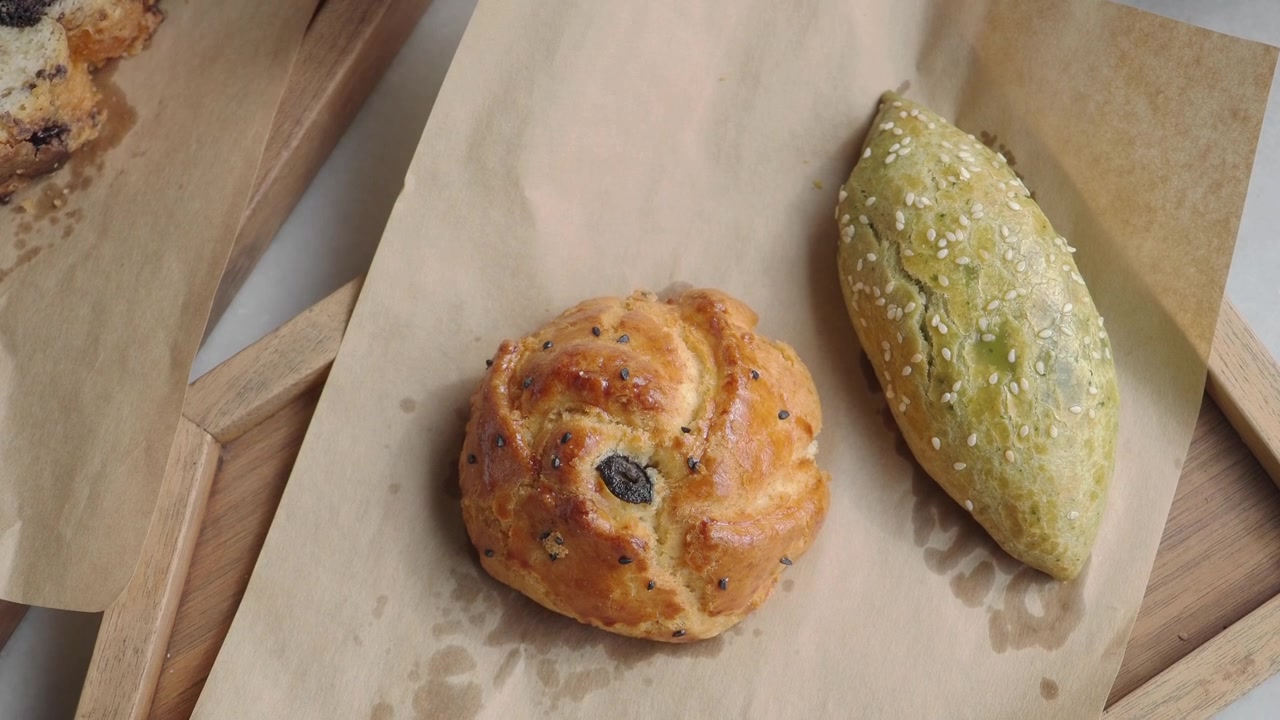 Hand Picking Up Green Pastry from a Tray of Baked Goods