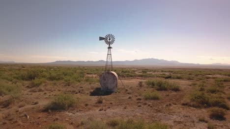 Tiro-Pan-Con-Drone-De-Un-Molino-De-Viento-Solitario-En-La-Madrugada-En-Un-Típico-Paisaje-Occidental-En-Algún-Lugar-En-El-Medio-Oeste-De-Los-Estados-Unidos-En-4k