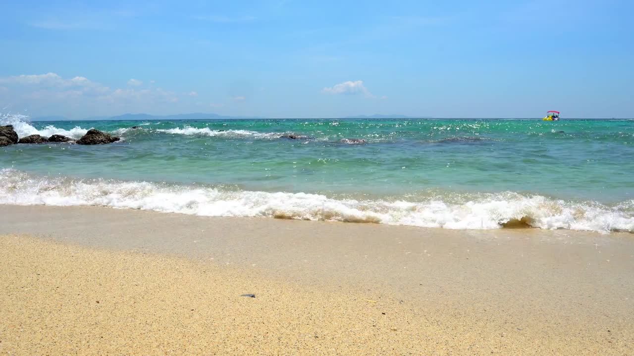 4km 풍경 선택적 초점 태양은 반이는 불꽃이 초록색 바다 표면과 바다 물 파도가 열대 모래 해변의 바위에 스프레이싱 하늘과 구름 배경