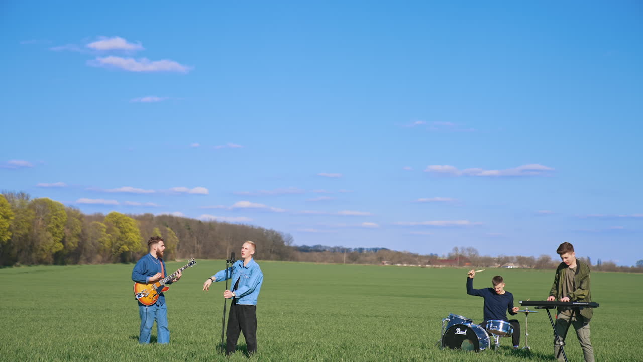 Musicians playing on field. Young musical band having concert on field