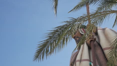 estatua de un hombre bajo una palmera