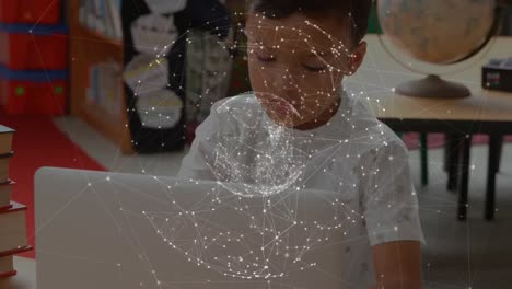 un globo de redes de conexiones girando contra un niño biracial que usa una computadora portátil en la escuela